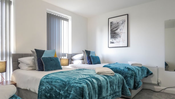 Habitación de hotel con dos camas, un ventanal grande, un radiador y una obra de arte enmarcada en la pared.