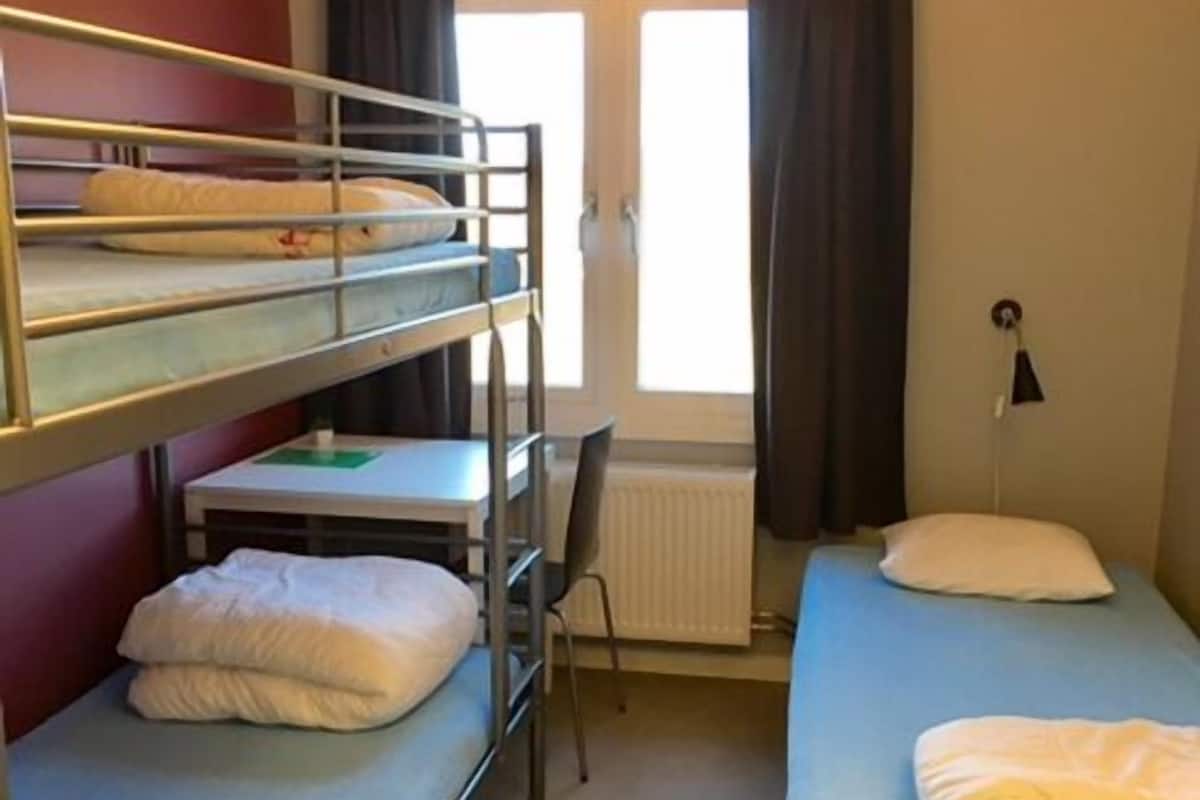 Une chambre de dortoir équipée de lits superposés, d’un bureau, d’une chaise et d’une petite table.