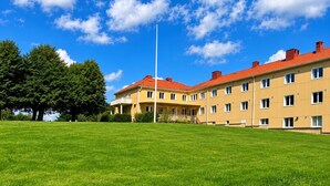 Un bâtiment doté de nombreuses fenêtres et d’un toit rouge, entouré d’une pelouse bien entretenue.