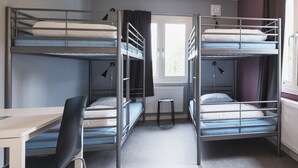 Ein Zimmer mit Etagenbetten, einem Schreibtisch und einem Stuhl.