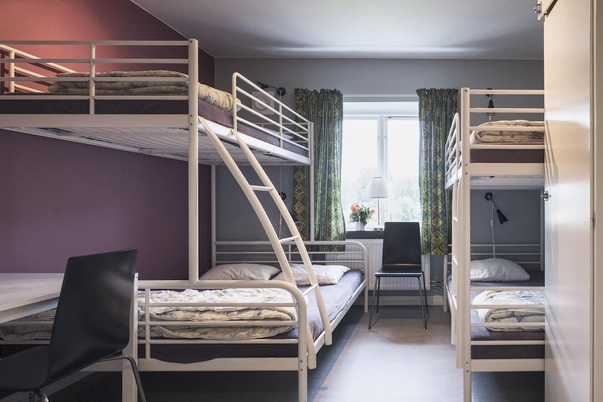 Une chambre de dortoir avec des lits superposés, un bureau, une chaise et une fenêtre avec des rideaux.