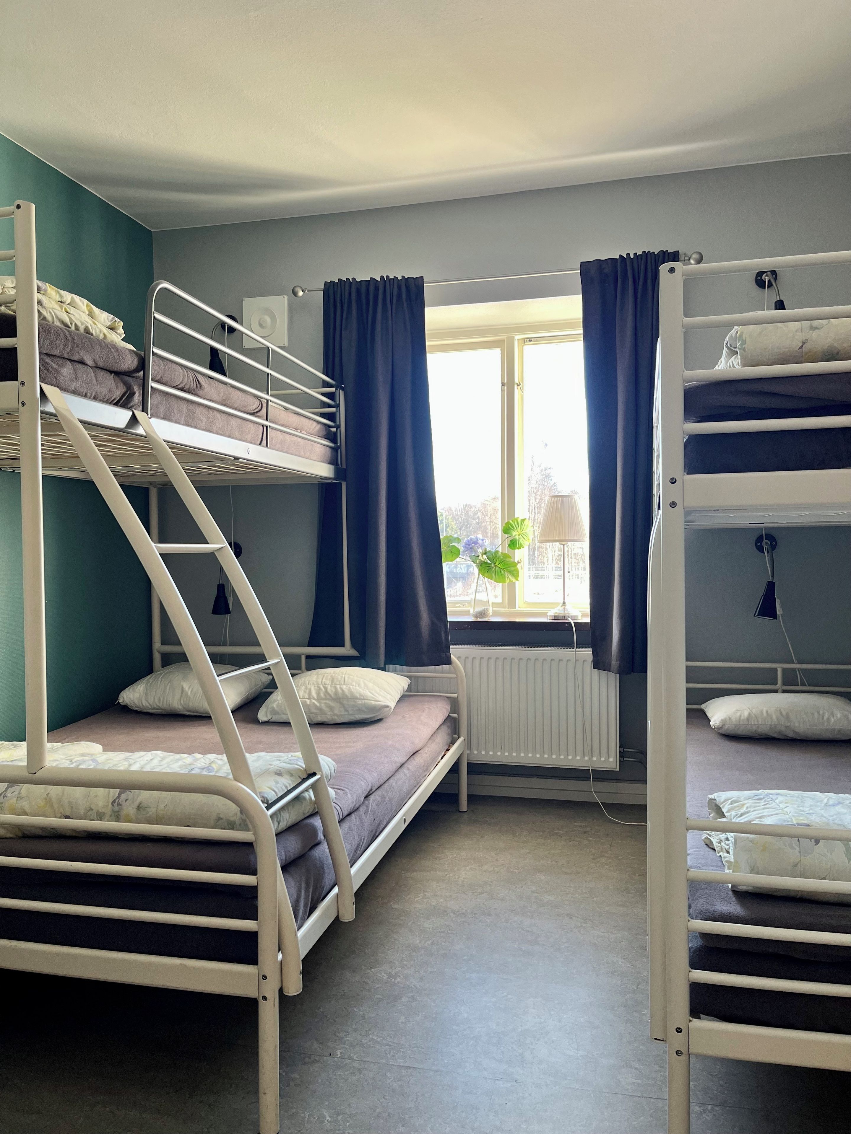 Un dormitorio con literas, un radiador y una ventana con cortinas.