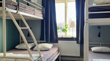 Un dormitorio con literas, un radiador y una ventana con cortinas.