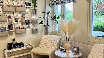 Una sala de estar moderna con un sofá, sillones, una barra para café y un estante de pared con varios objetos.
