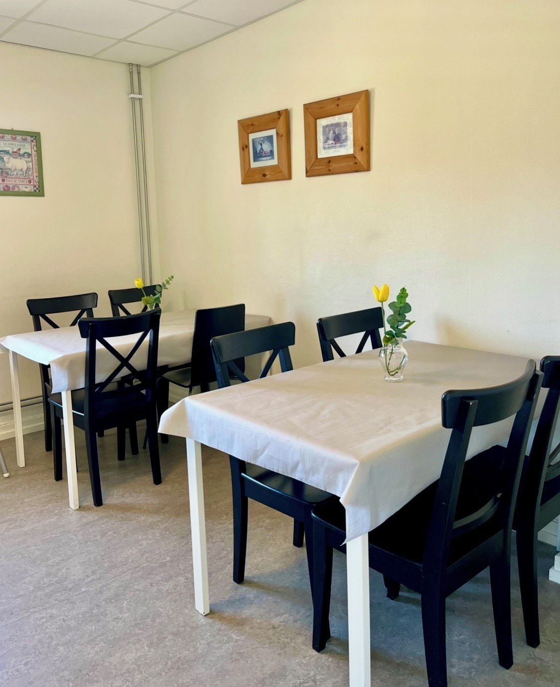 Un comedor con una mesa dispuesta para cuatro personas, rodeada de sillas, y un florero con flores sobre la mesa.