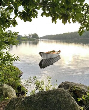 Un lac paisible, avec un bateau à la dérive sur l’eau, entouré de rochers et d’arbres.