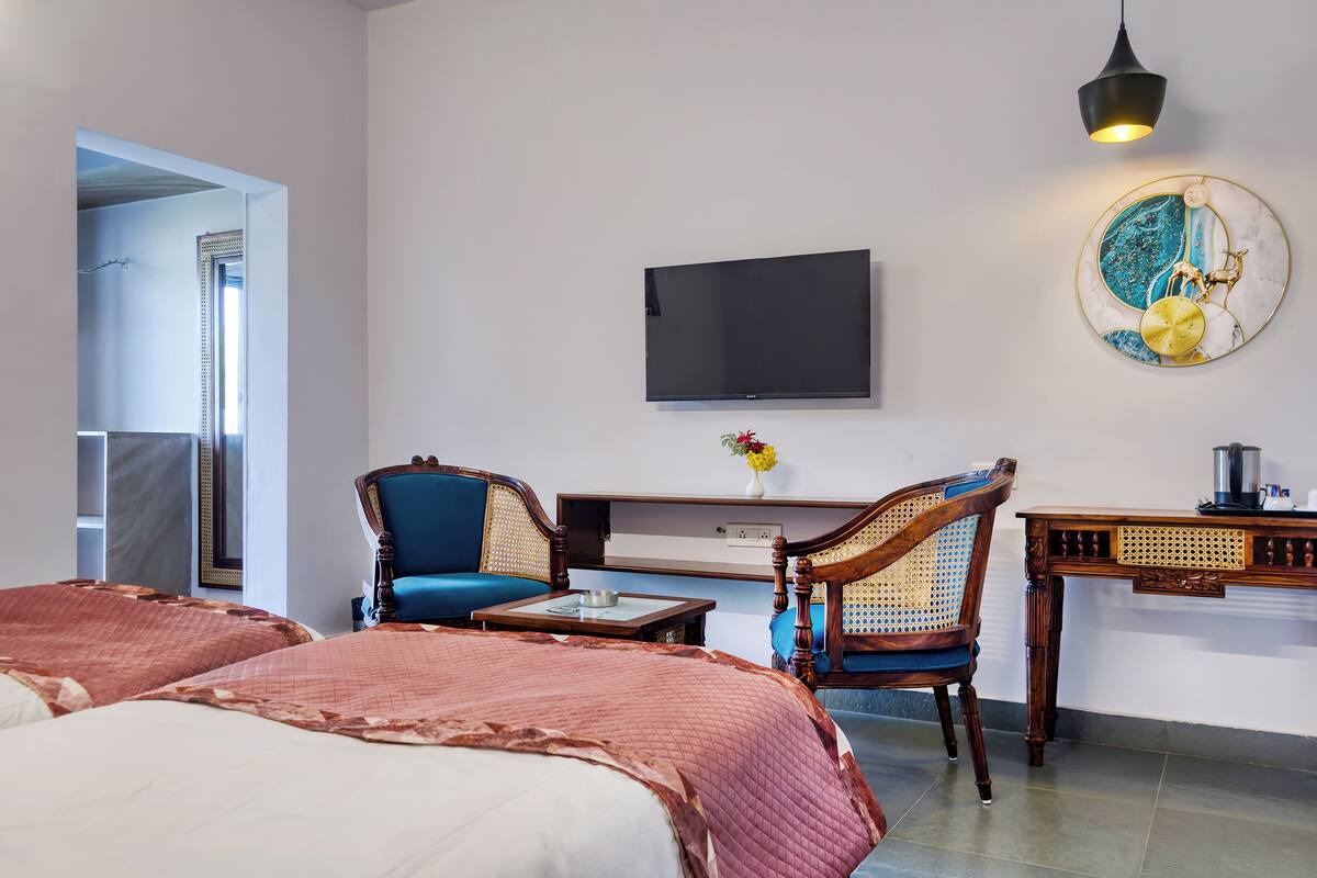 Une chambre d’hôtel avec deux lits, une télévision, un bureau avec une chaise et un élément décoratif mural.