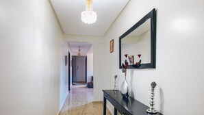 A hallway with a black console table, a large mirror, and a chandelier. - amazing appartement in center city (Marrakesh)
