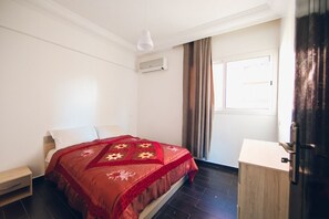 A bedroom with a bed, a bedside table, a wardrobe, and a window with curtains. - amazing appartement in center city (Marrakesh)
