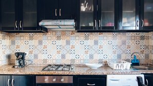 A kitchen with black cabinets, a patterned backsplash, a gas stove, a coffee maker, a dish rack, and a washing machine. - amazing appartement in center city (Marrakesh)