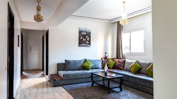 A modern living room with a grey sofa, colorful cushions, a coffee table, and a chandelier. - amazing appartement in center city (Marrakesh)