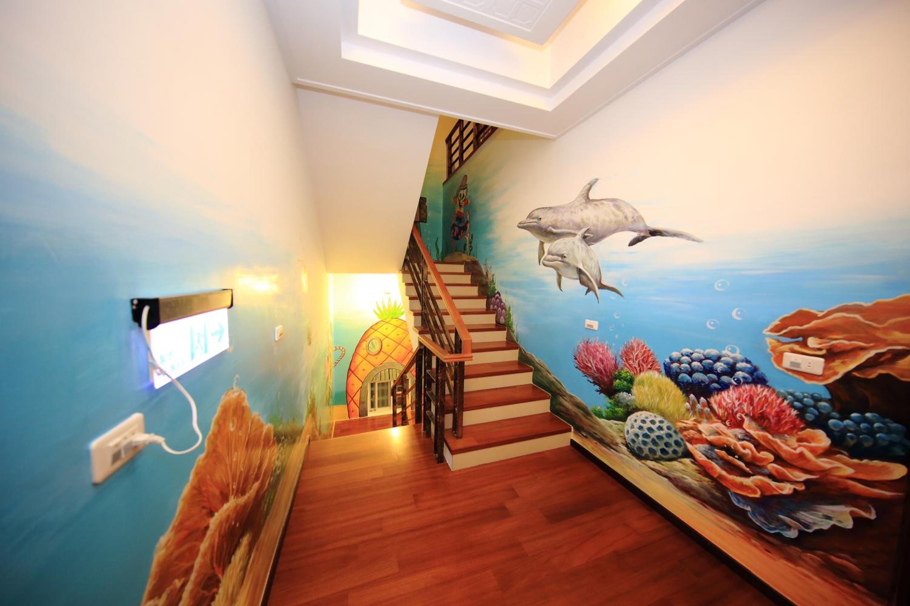 Uma escadaria com um mural de vida marinha que leva a um quarto com vista para o oceano.