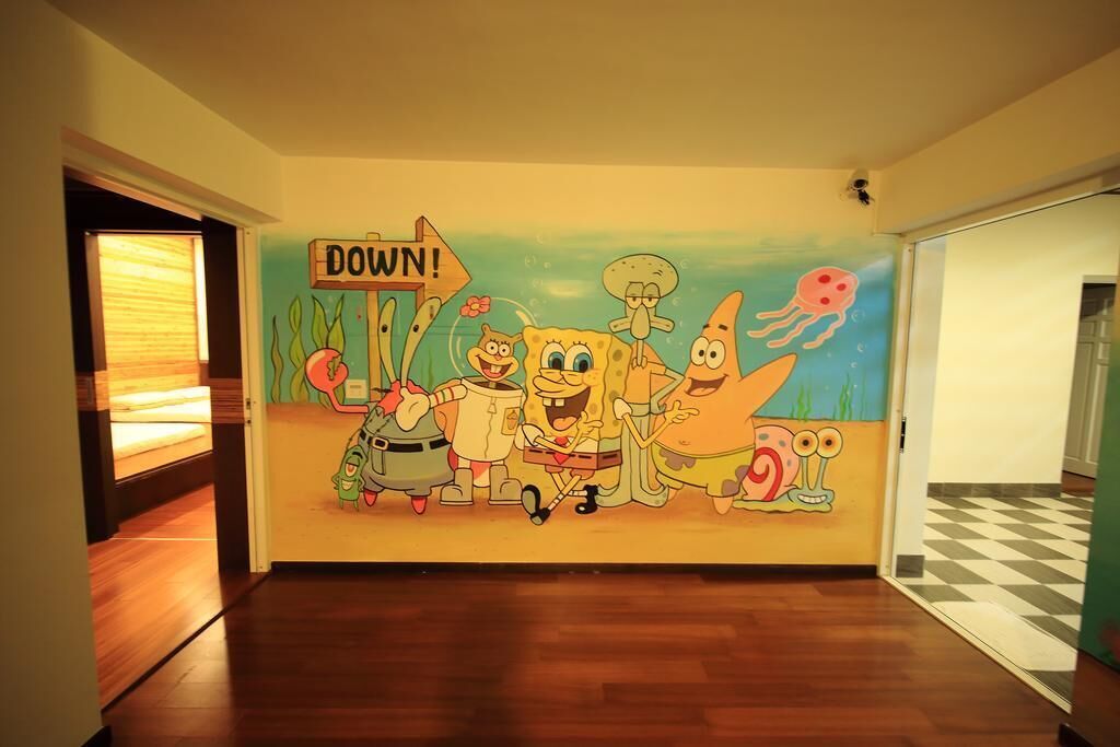 Um corredor com um mural de personagens de desenho animado e um aviso indicando 'DOWN'.