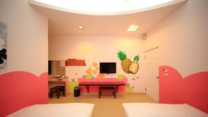 Een kamer met twee bedden, een bureau, een stoel, een televisie en een muur met een ananas decoratie.