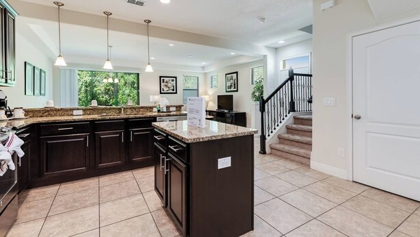 A modern kitchen with dark cabinetry, granite countertops, and pendant lighting. - Elegant and Spacious 4BD Home Near Disney and Minutes From Florida's top Golf Courses! #8197 (Davenport)