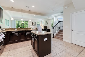 A spacious kitchen with dark cabinetry, granite countertops, and pendant lighting.