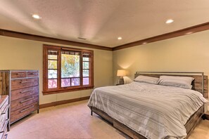 Relax in this serene bedroom with a large bed, dresser, and window offering a view of the outdoors.