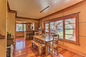 Enjoy meals in this dining area with a large table and comfortable chairs, surrounded by natural light and a kitchen.