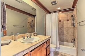 Bathroom features a large mirror, sink, and shower area with a handheld showerhead.