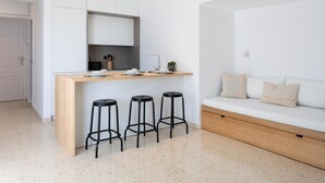 Una cocina moderna con encimera de madera, tres taburetes negros y un sofá blanco con cojines.