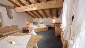 A cozy room with a wooden ceiling, a bed with white linens, a wooden table with candles, and a patterned floor. - Hotel Gasthof Eder (Gmund am Tegernsee)