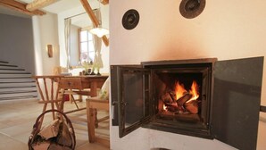 A cozy room with a fireplace, a dining table, and chairs. - Hotel Gasthof Eder (Gmund am Tegernsee)
