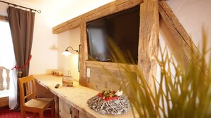 A rustic wooden room with a wooden table, a chair, a TV mounted on a wooden wall, and a lamp. - Hotel Gasthof Eder (Gmund am Tegernsee)