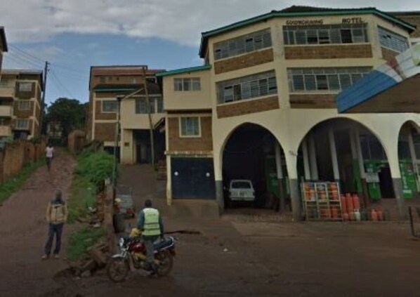 Un edificio de dos pisos con un letrero que dice "Hotel". Hay dos arcos en la entrada, y un coche aparcado en el interior.