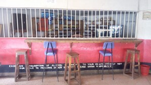 Una zona de bar con mostrador, taburetes y una ventana con barrotes.