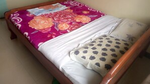 Una cama con colcha estampada, almohadas blancas y cabecera de madera.