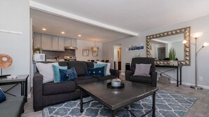 A modern living room with a dark sofa, a coffee table, and a patterned rug. - Modern Condo with Shared Hot Tub! Short Walk to Village! (Mammoth Lakes)