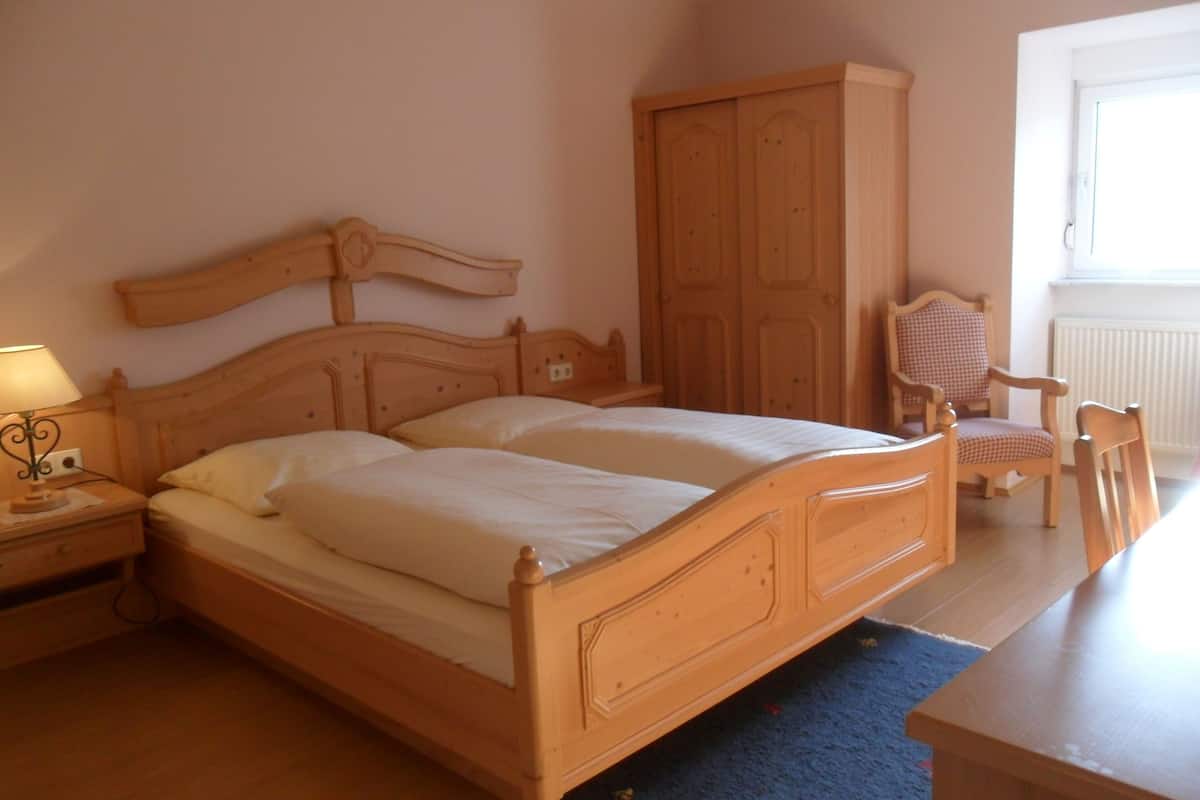 A bedroom with a wooden bed, a nightstand, a chair, and a wardrobe.
