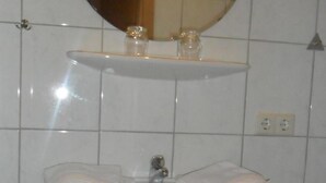 Een badkamer met een wit wastafel, een spiegel erboven en een betegelde muur.