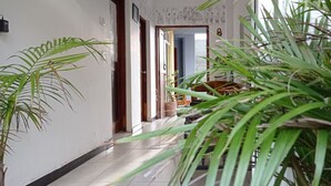 A hallway with a tiled floor, a wooden door, and a view into a room with a table and chairs. - Villa Forest View (Kandy)