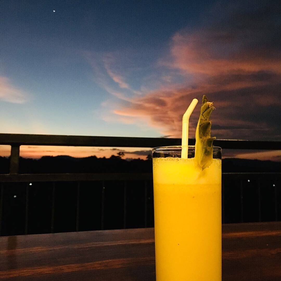 Un verre contenant une boisson jaune, avec une paille et une garniture, posé sur une surface en bois.