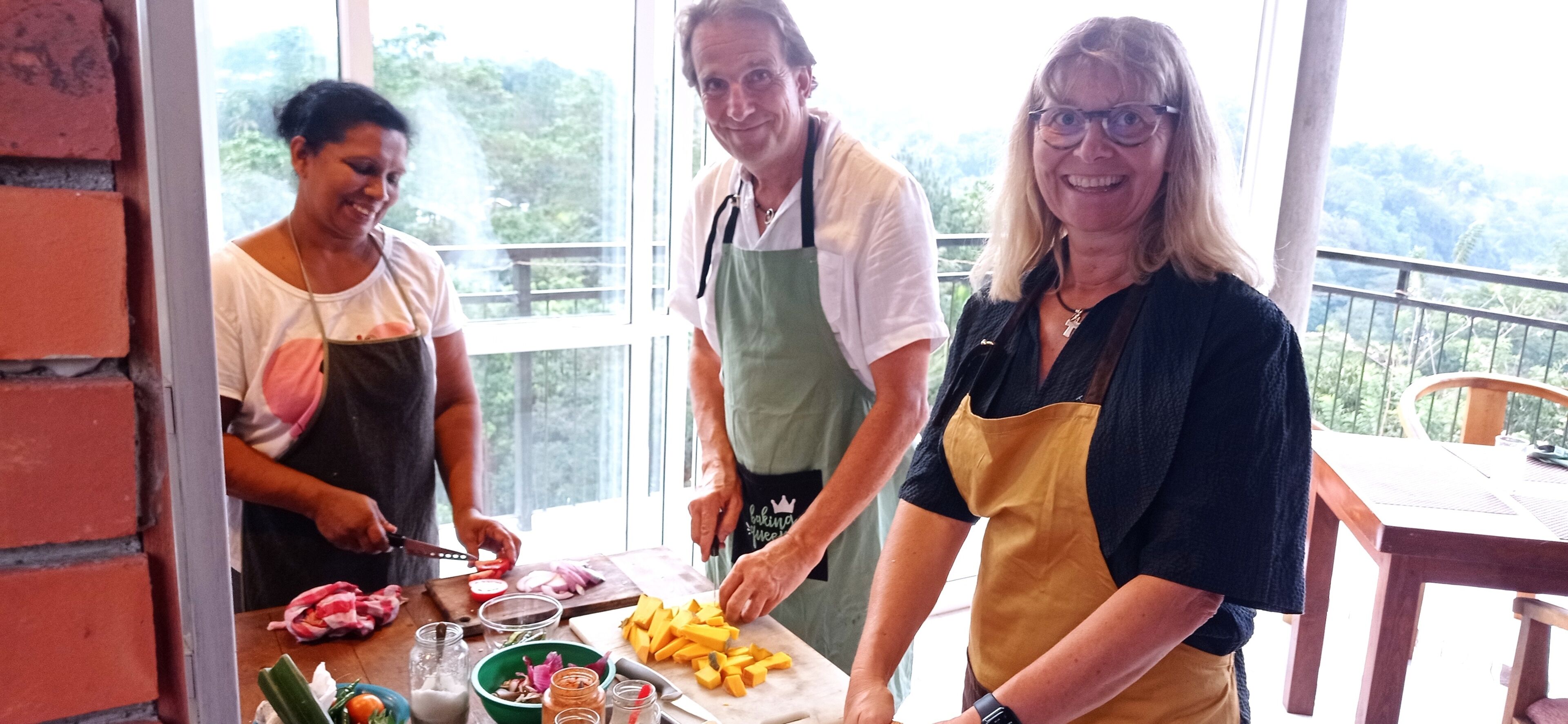 Three people preparing food at a table with various ingredients and kitchen tools.