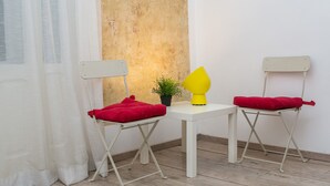 A room with a white table, two white folding chairs, a small potted plant, and a yellow lamp. - Apartment Piano (Belgrade)
