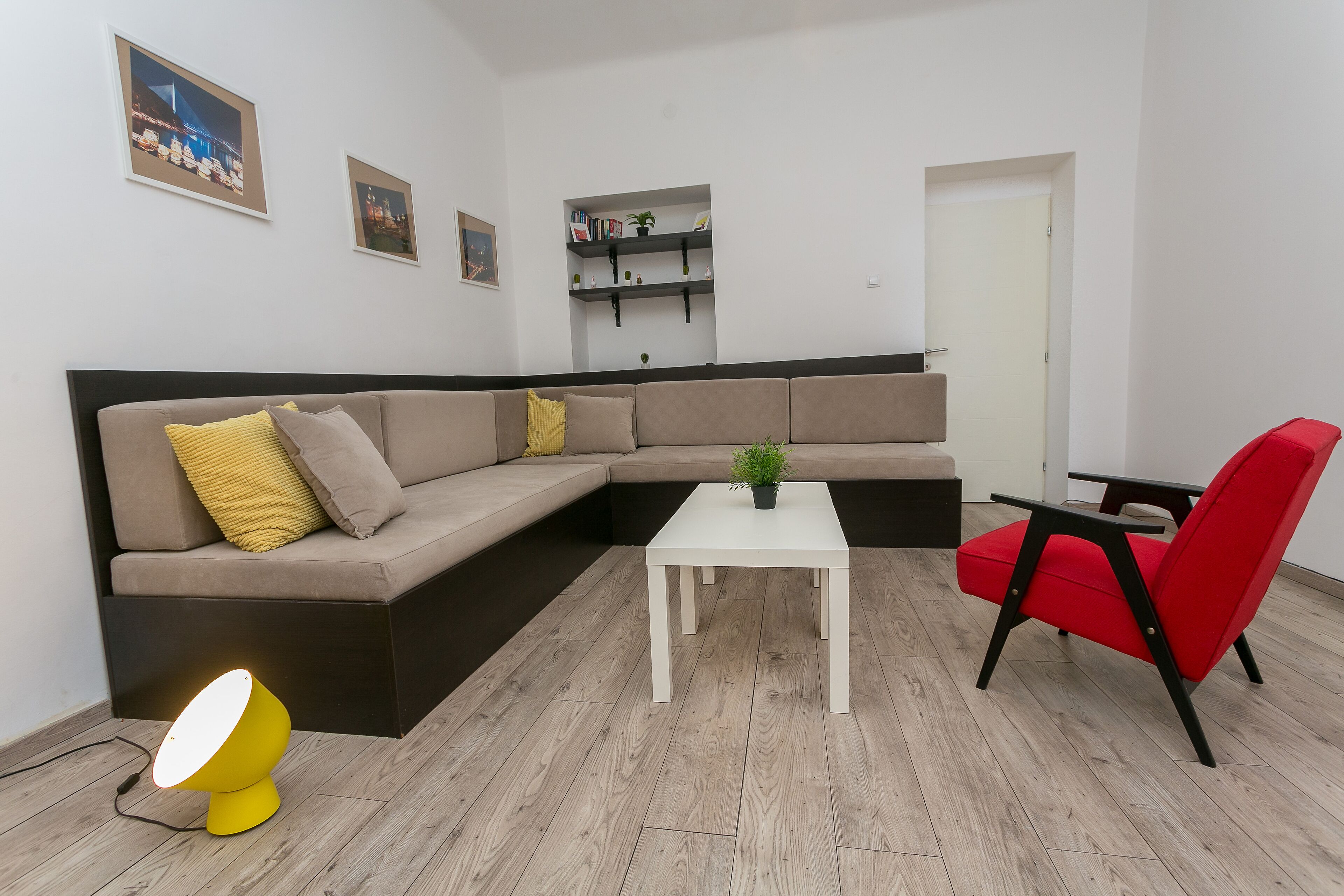 A modern living room with a sectional sofa, a red chair, a white coffee table, and a yellow floor lamp.