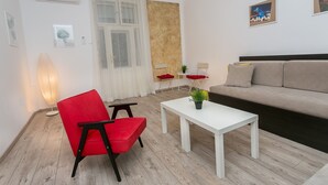 A modern living room with a red chair, white coffee table, and a beige sofa. - Apartment Piano (Belgrade)
