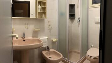 A bathroom with a sink, bidet, toilet, and a glass-enclosed shower.