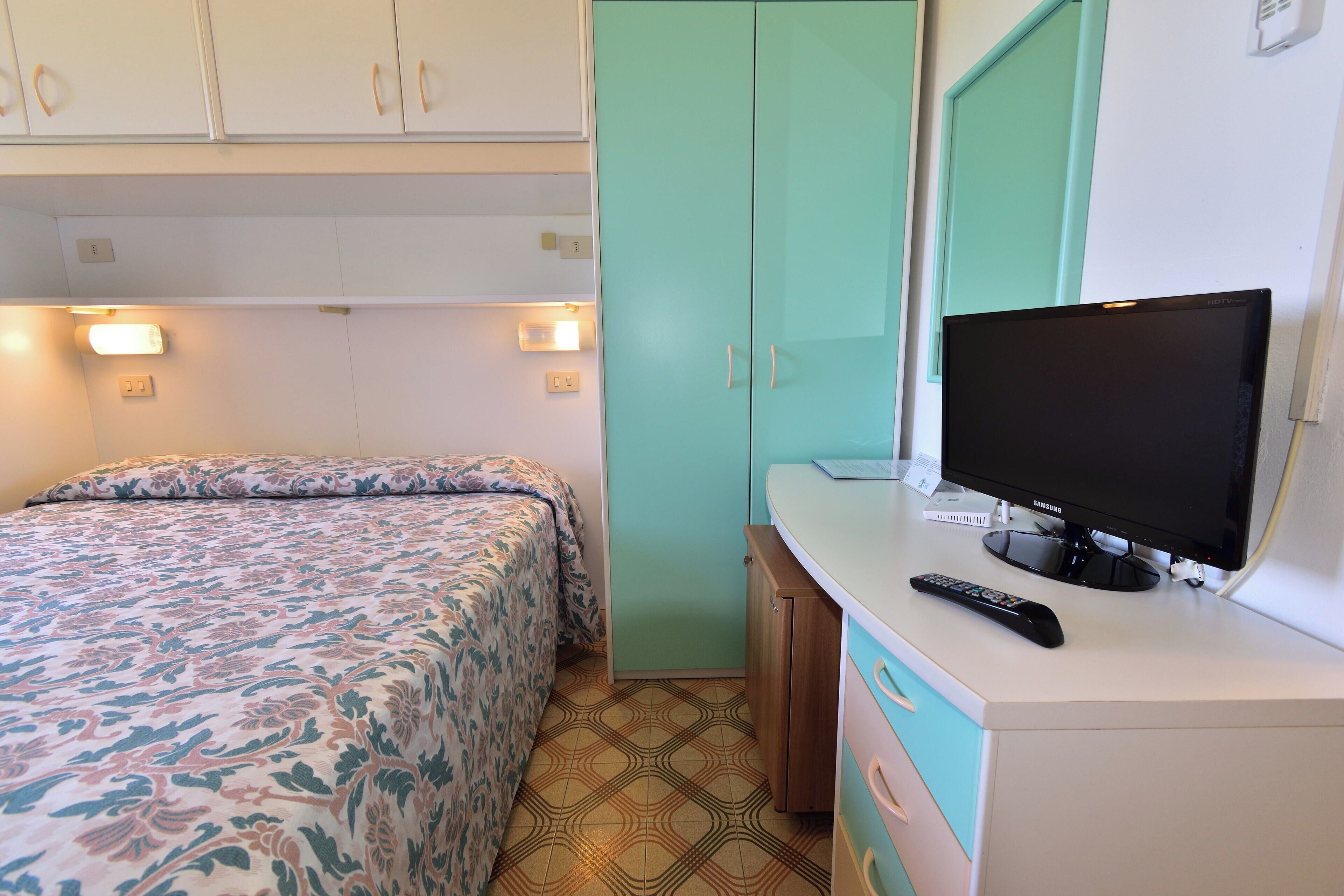 A bedroom with a bed, a television, and a wardrobe.