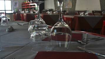 Mesa de comedor preparada con copas de vino, cubiertos y una servilleta roja.