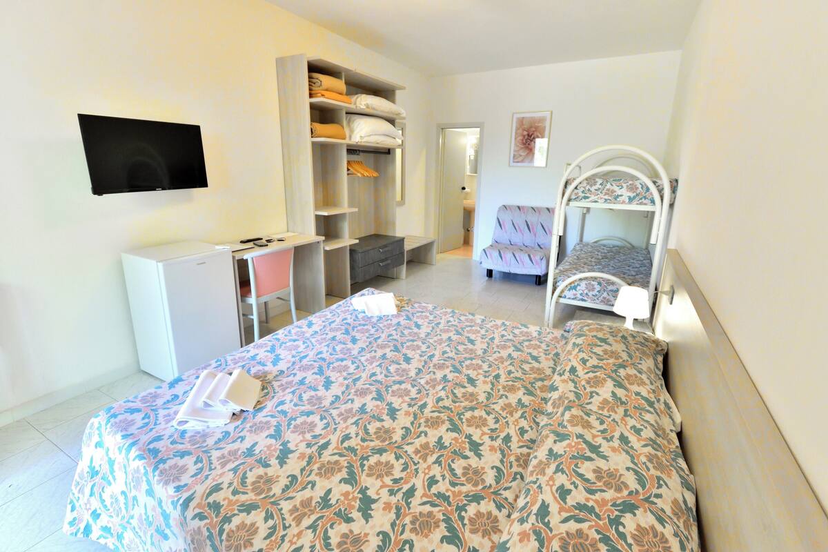 Un dormitorio con cama, escritorio, armario y televisor.