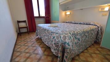 Une chambre à coucher avec un lit, une chaise, une armoire et une fenêtre avec des rideaux.