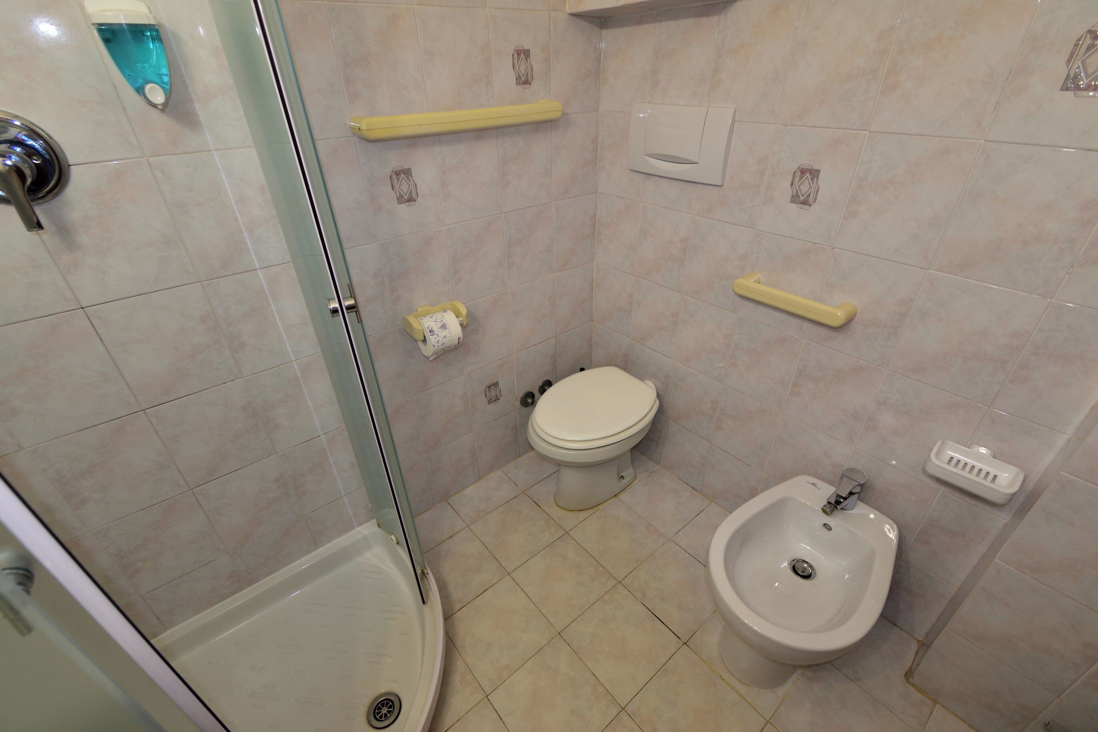 A bathroom with a glass-enclosed shower, a toilet, a bidet, and a sink.