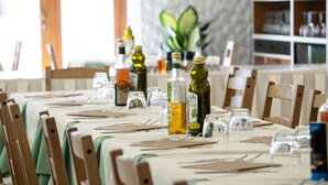 Een eettafel compleet met stoelen, wijnflessen en glazen, wat wijst op een restaurant.