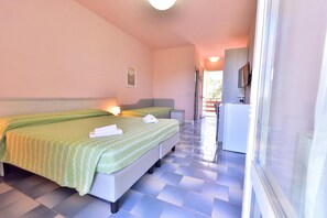 Habitación de hotel con una cama grande, una mesita de noche, un escritorio pequeño y un televisor.