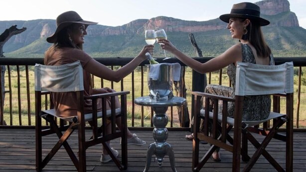 Deux personnes trinquent à une table, avec une vue sur les montagnes.