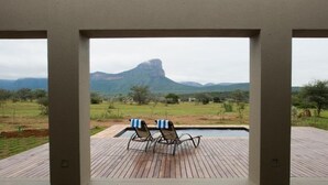 Un espace aménagé au bord de la piscine, avec deux chaises longues et une vue sur un paysage montagneux.