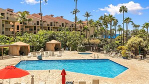 A resort pool area with a large rectangular pool, lounge chairs, umbrellas, and palm trees. - Kamaole Sands 3-308, Premier Location, Renovated, Large Lanai, Wi-Fi, Split AC!  (Kihei)